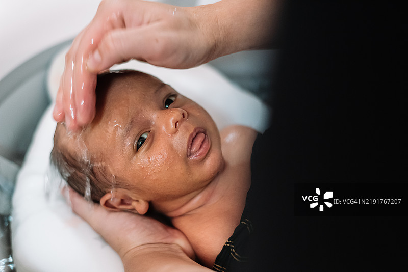 母亲在给新生儿洗头。图片素材