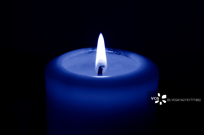 黑色背景下的蓝色蜡烛烛光图片素材