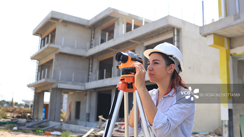 女性测量工程师或土木工程师在住宅施工现场使用水平测量仪器图片素材