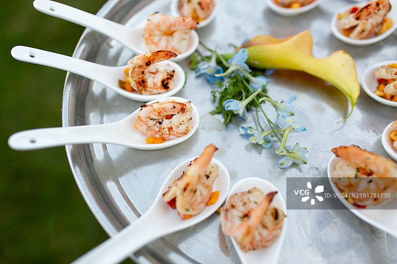 小勺盛着的烤虾，放在银色托盘上图片素材