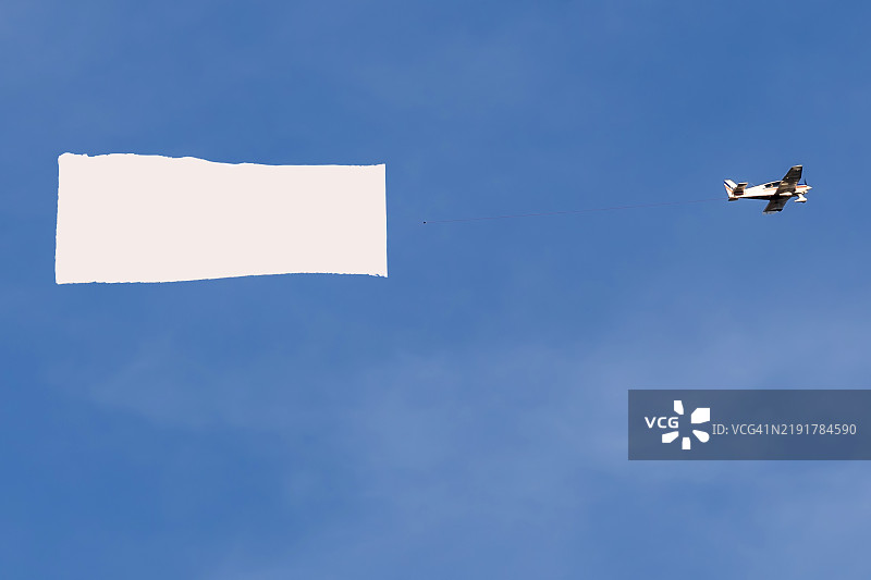 天空中飞行的带有广告横幅的飞机图片素材