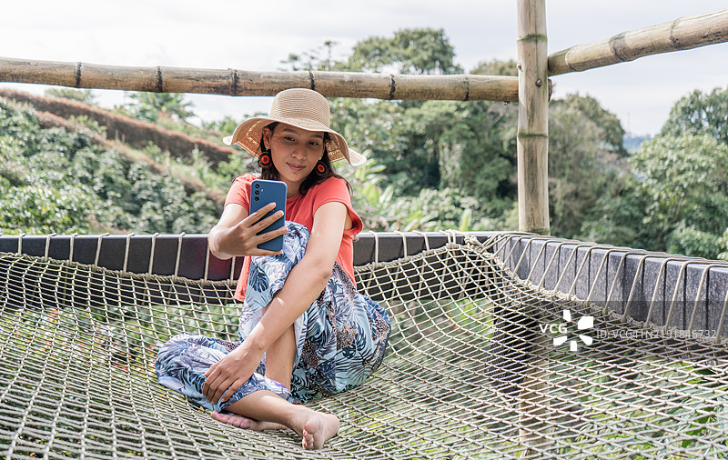 游客在咖啡种植园的吊床上放松时自拍图片素材