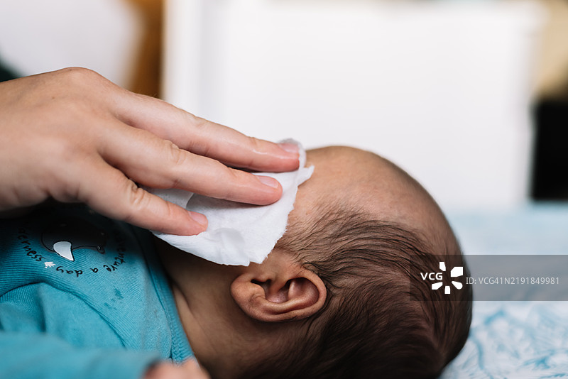 母亲用纱布擦拭宝宝的脸庞图片素材