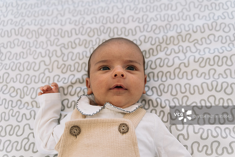 穿着西装和工装裤的优雅宝宝躺在床上。图片素材