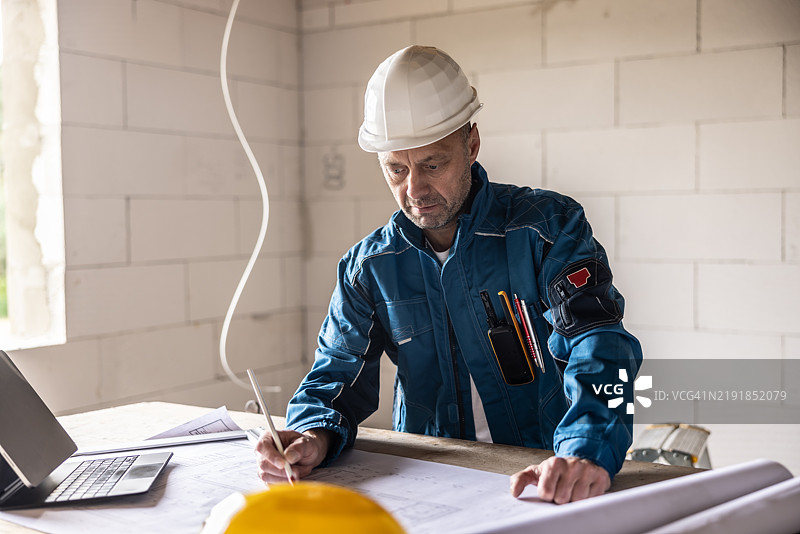 一名成年工人在施工现场直接检查建筑计划。图片素材
