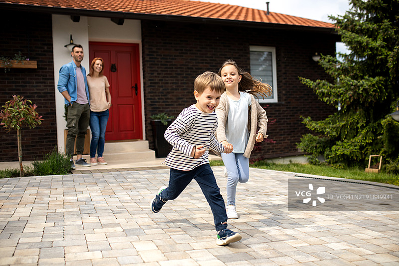 美丽的年轻家庭与孩子们在房子前快乐地玩耍图片素材