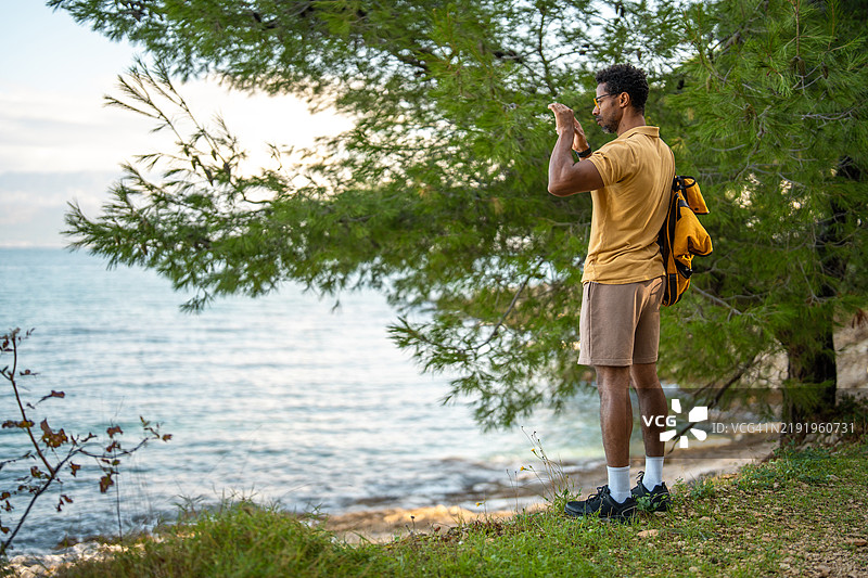 平静的黑人男性探险者在海岸拍摄自然照片图片素材