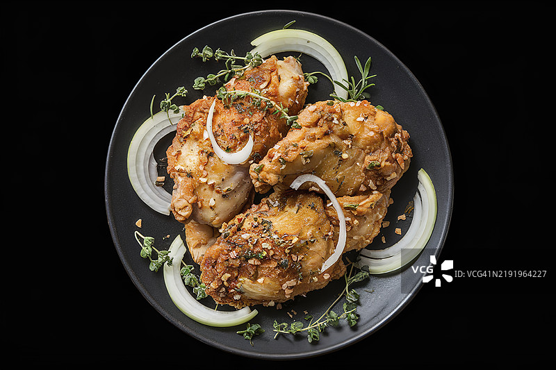 一盘孤立的炸鸡肉，上面放着洋葱和香草图片素材