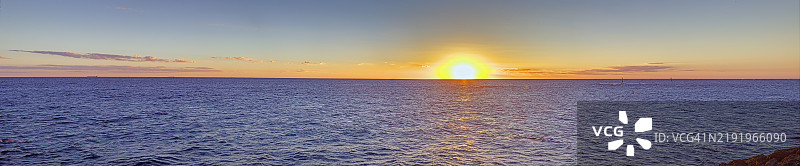 宁静的海洋地平线上绚丽的日落，融合了鲜艳的橙色和蓝色调，唤起宁静感。图片素材