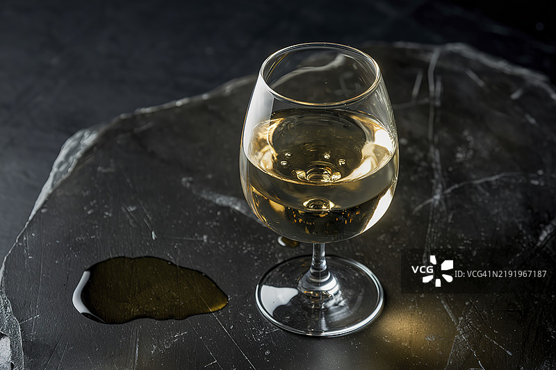 一杯白葡萄酒放在黑色石材背景上图片素材