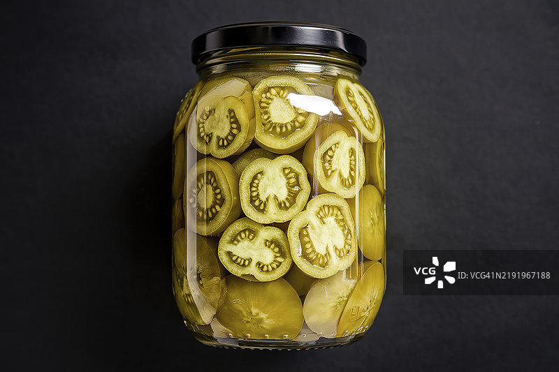 一个装满绿色腌制切片番茄的透明玻璃罐的照片图片素材