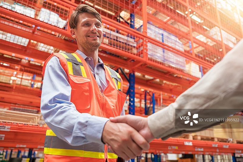 仓库经理与仓库中的男性员工握手。仓库员工握手。图片素材