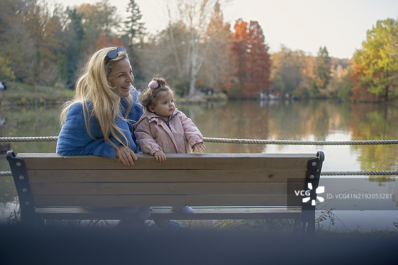 母亲和宝宝在湖边享受美丽的秋日图片素材