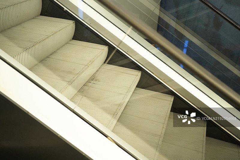 透视图显示一部扶梯，通过玻璃可以看到几乎完全展开的踏板和传送带。图片素材