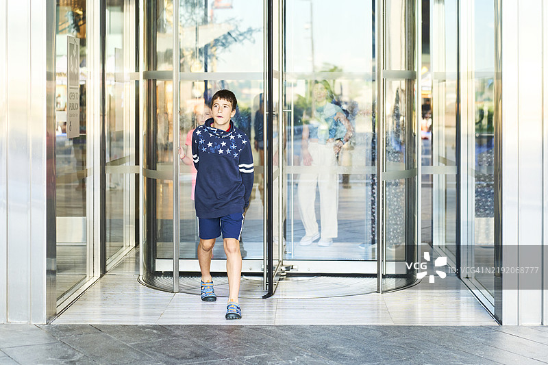 孩子走出现代建筑的旋转门图片素材