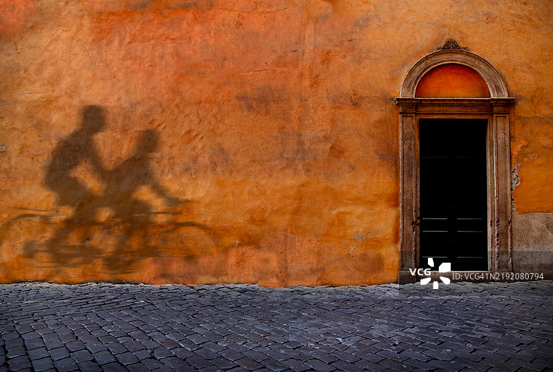 自行车骑士的影子映在墙上。图片素材
