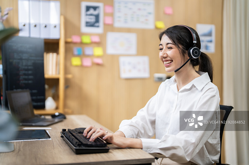 友好的客户支持代表在明亮的办公室中使用耳机和电脑图片素材