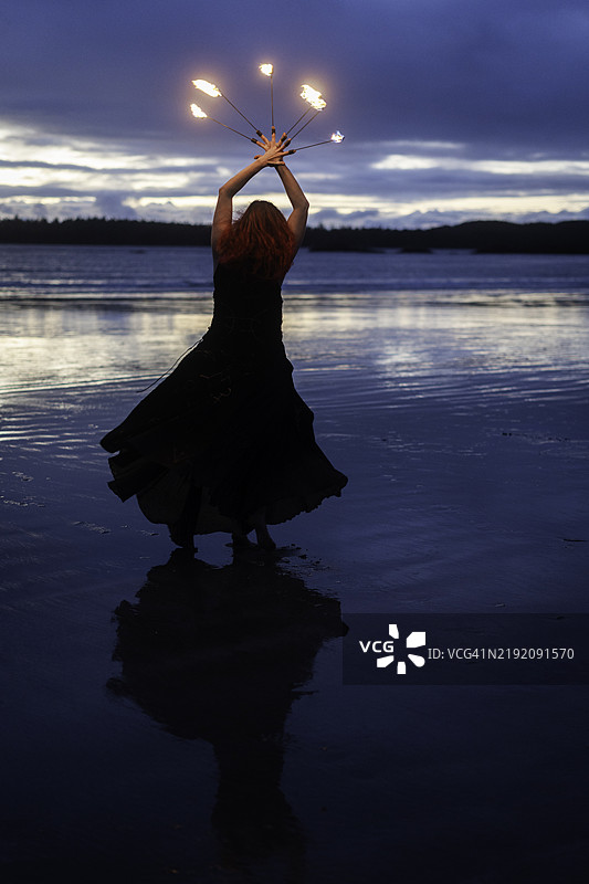 在海滩上跳舞的女性，手指上燃烧着火焰图片素材