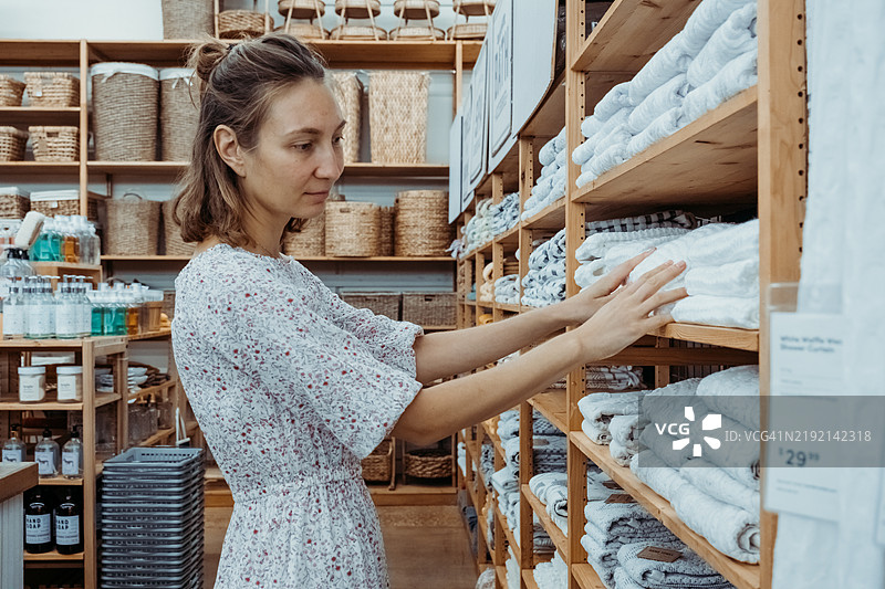 年轻女性在专注于整理和装饰的商店购物，寻找家居必需品。图片素材