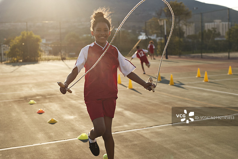 在学校操场上跳绳的微笑女孩图片素材