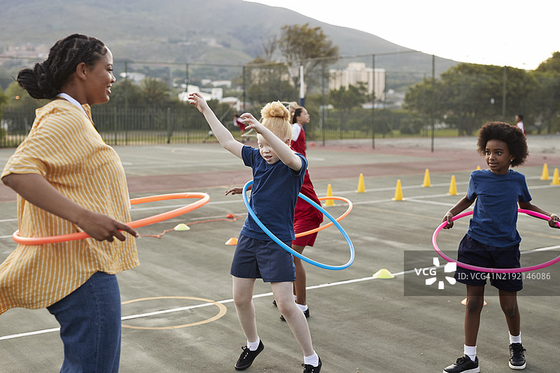 教练在学校操场上用塑料圈训练女孩们图片素材