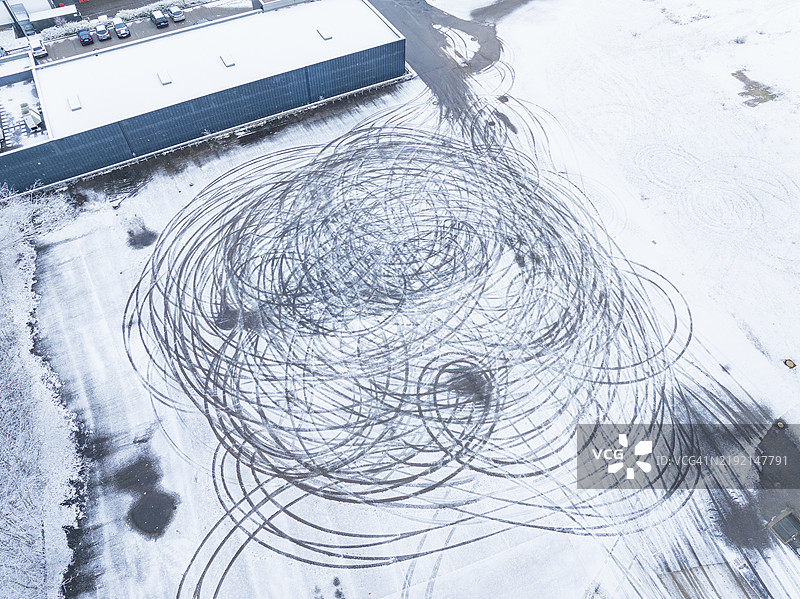 轮胎痕迹在德国黑森林纳戈尔德的雪覆盖表面上形成大圆圈，从空中俯瞰。图片素材