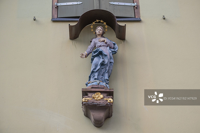 德国巴伐利亚州丁克尔斯比尔的房屋上方的圣母玛利亚雕像与华盖图片素材