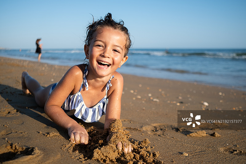 海滩上躺在沙子里的女孩肖像（6-7岁）图片素材