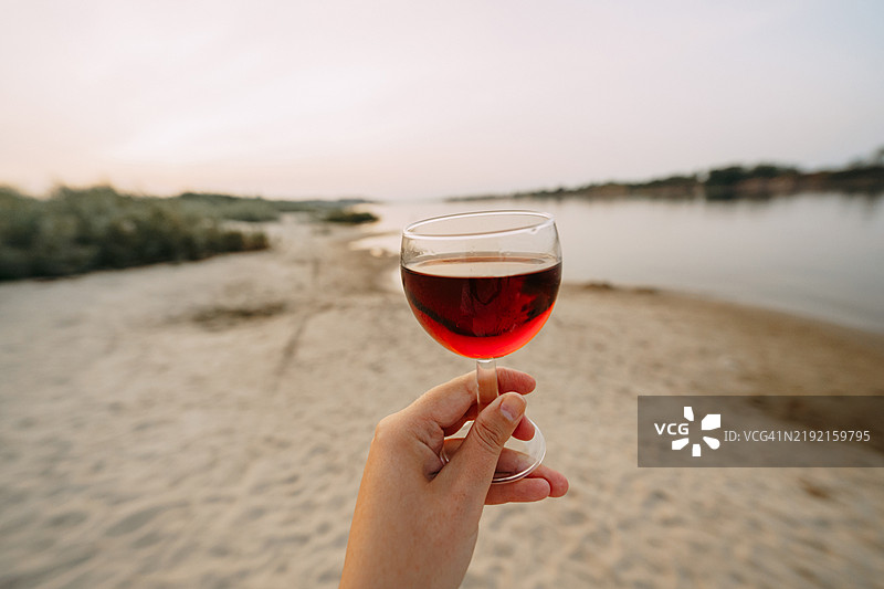海滩日落时手握酒杯图片素材