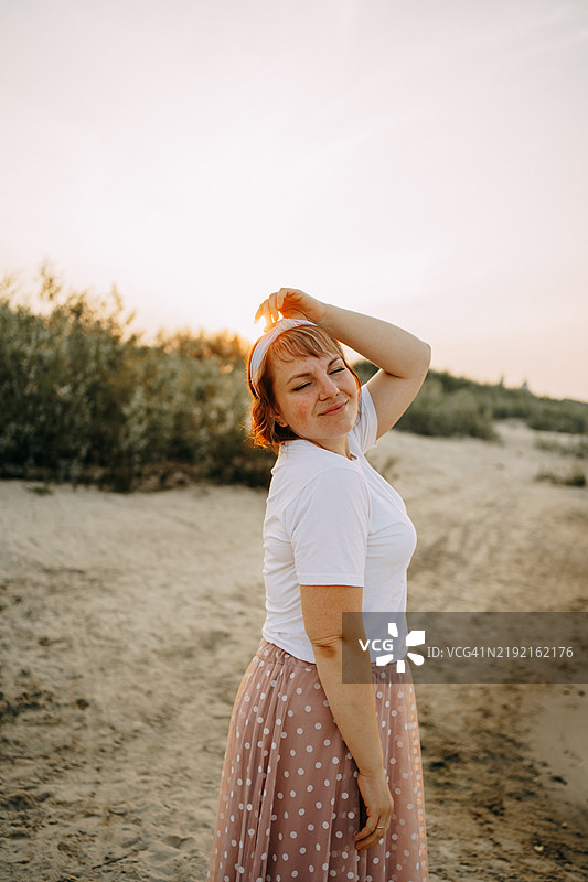 年轻女性在沙滩上享受日落图片素材