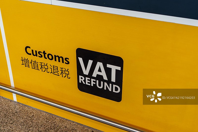 海关办公室的鲜艳黄色标志特写，指示增值税退款，可能位于机场或交通枢纽。图片素材