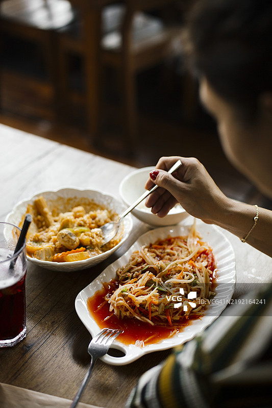 传统泰式青木瓜沙拉，辛辣酸爽的青木瓜沙拉，配以新鲜香草、辣椒和青柠汁，正宗泰国街头美食，盛放在白色盘子里，营造出温馨的用餐环境图片素材