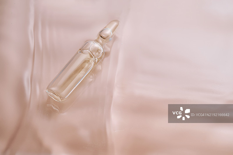 米色背景上的安瓿瓶与水图片素材