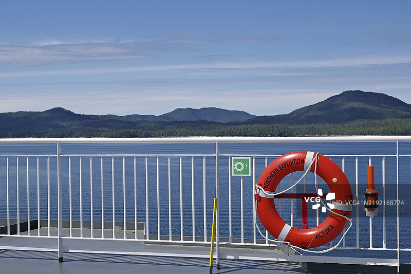 从船上看到的海景，背景是清澈的天空和山脉，旁边有一个救生圈，BC Ferries渡轮在内海航道上驶向普林斯鲁珀特。图片素材
