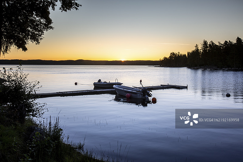 瑞典阿尔扬格的格林斯比营地附近的码头上停着的船只在日出时分图片素材