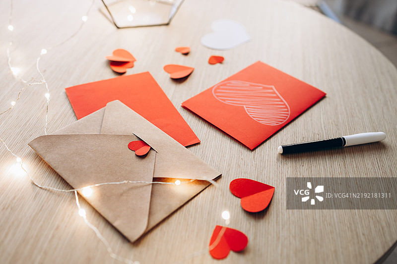 情人节写信的布置，配有信封、手工心形装饰和 fairy lights。图片素材