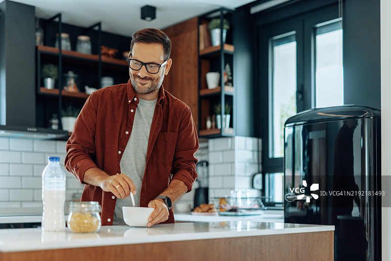 快乐的男人在现代厨房准备早餐图片素材
