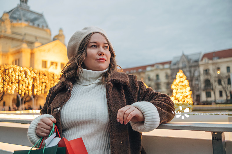 美丽的女人在装饰着圣诞节的萨格勒布夜晚街头手捧礼物图片素材