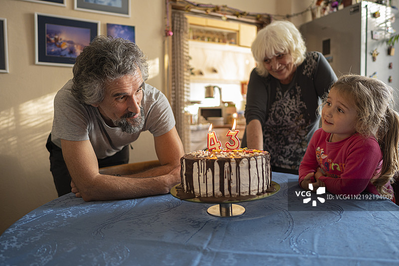 生日蛋糕惊喜。多代同堂的家庭聚会在家中举行图片素材