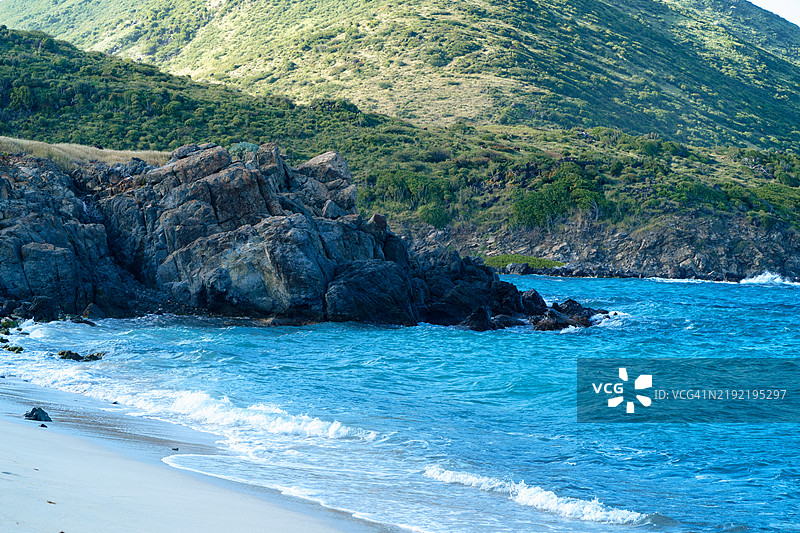 圣马丁的岩石海岸线，碧蓝的海浪和郁郁葱葱的山丘图片素材