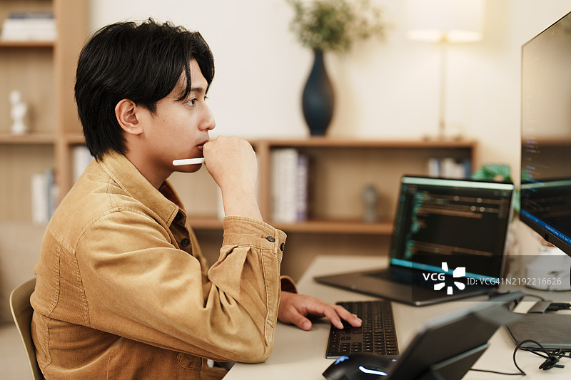 专注的程序员在现代工作空间中分析双屏显示器上的代码图片素材