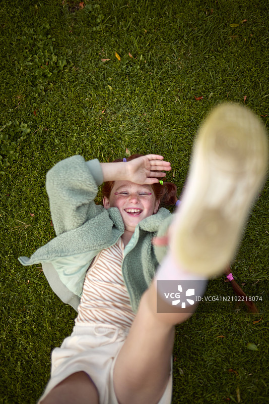 快乐女孩在绿色草地上向天空伸手图片素材