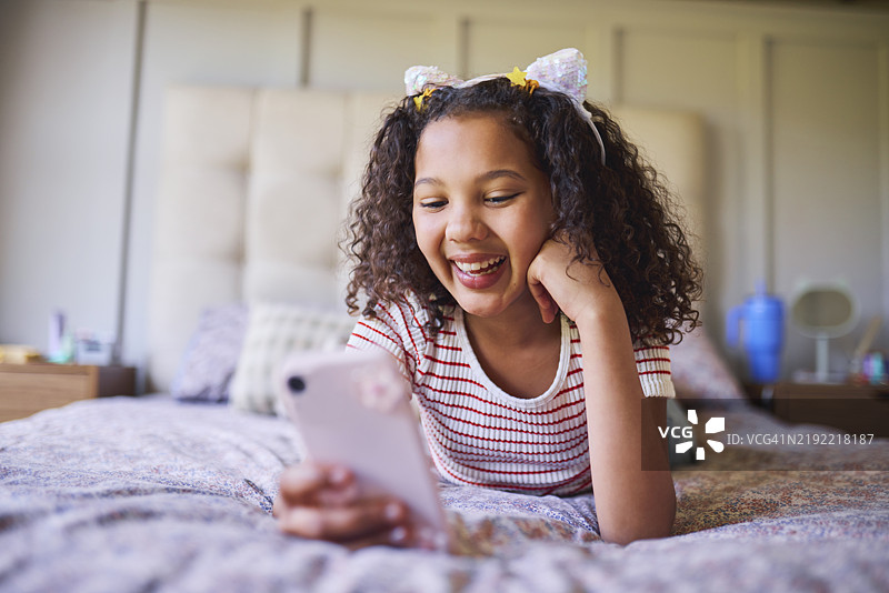 孩子的乐趣：卧室里的手机乐趣图片素材