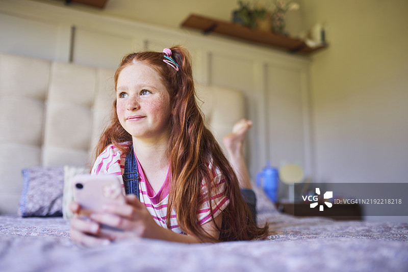 梦幻女孩躺在床上玩手机图片素材