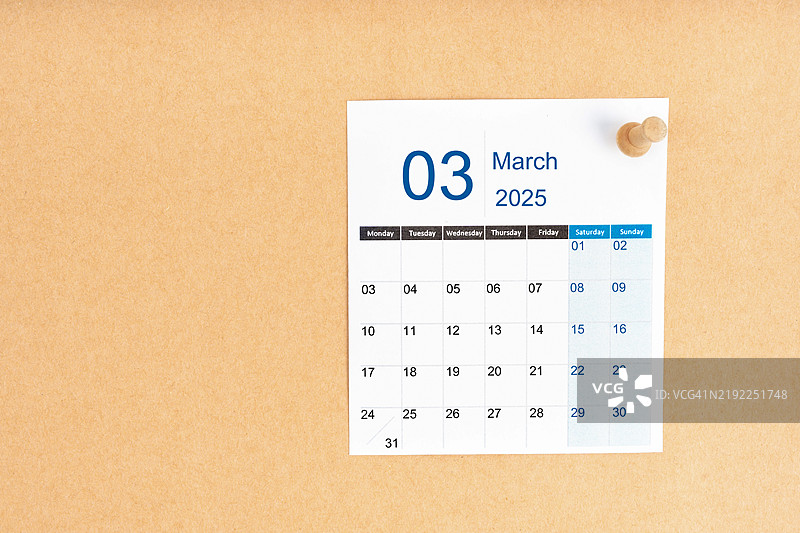 2025年3月的日历，木制图钉放置在棕色背景上，留有空白空间。图片素材