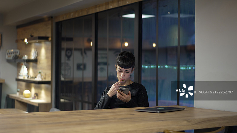 专注的年轻女性在现代办公室夜间使用智能手机图片素材