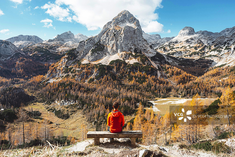 坐在长椅上享受秋季山景的人图片素材