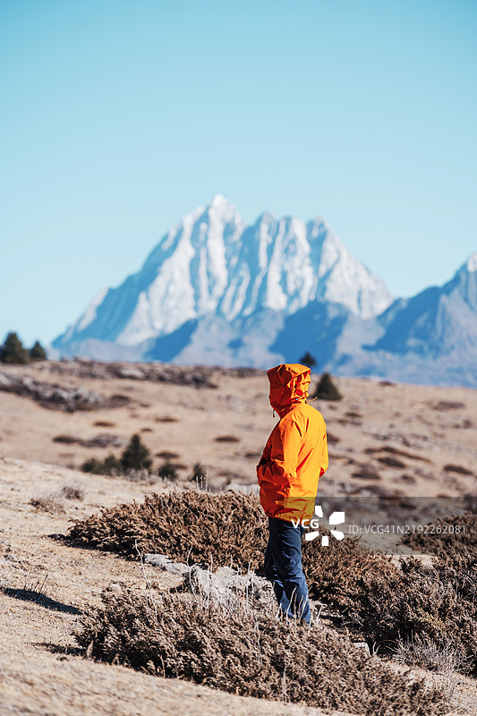 一个男人站着，凝视着雪山。图片素材
