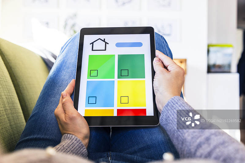 女性在沙发上舒适地使用平板电脑的应用程序控制节能家电设备图片素材