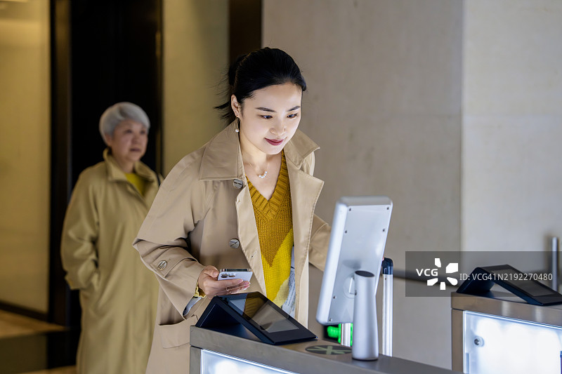 两位亚洲商务人士使用面部识别技术打开办公大楼的门。图片素材